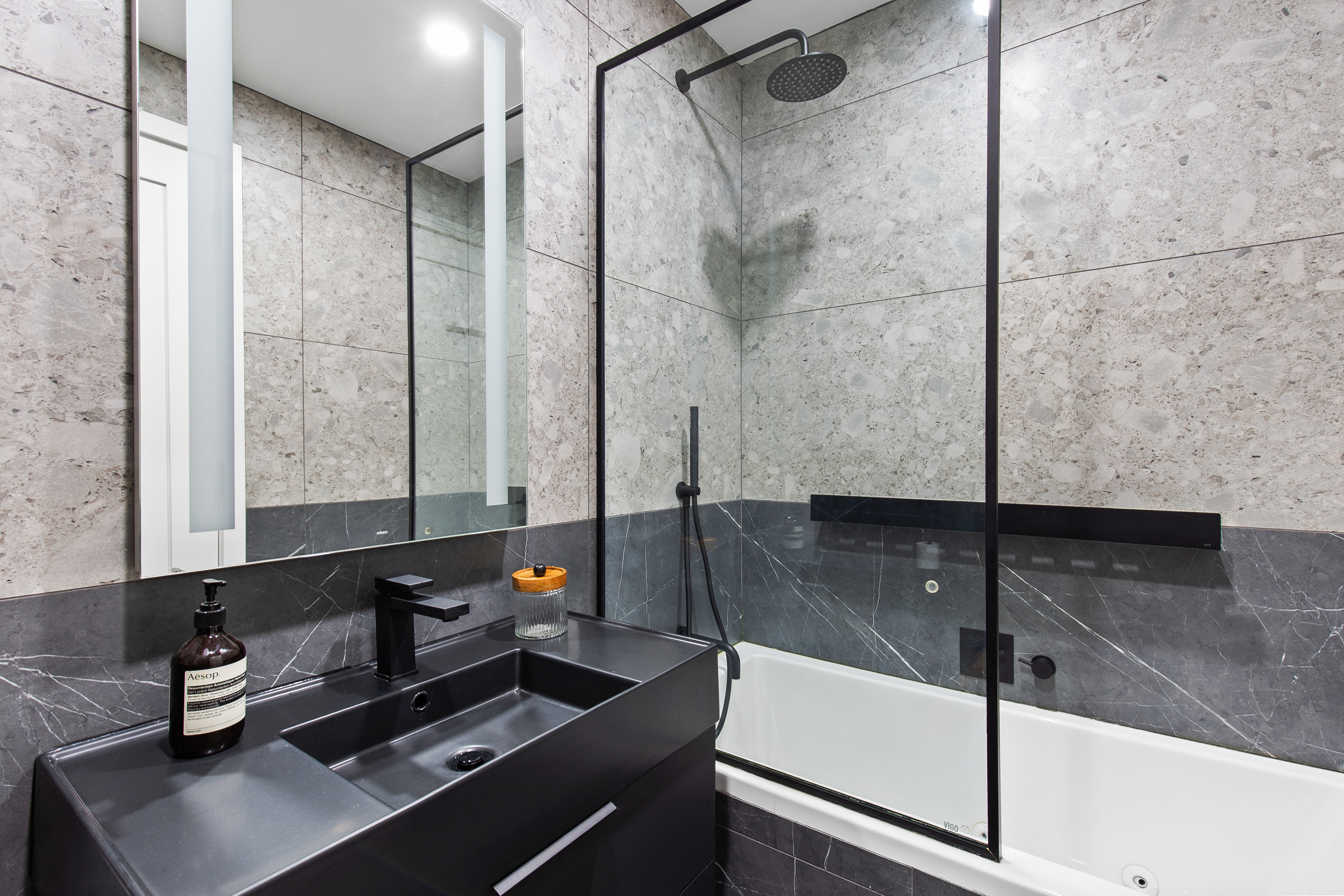 Bathroom — terrazzo tile, black fixtures, tub